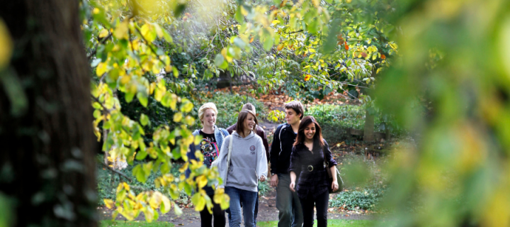 photo shows students walking on campus in and amongst trees