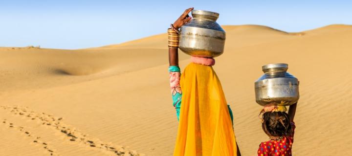 Woman and child carrying water in desert in India
