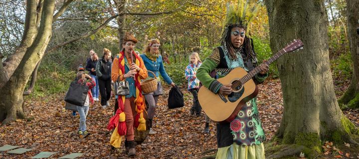 Mythical performers dressed in colourful, mystical outfits lead local school children through the woods.