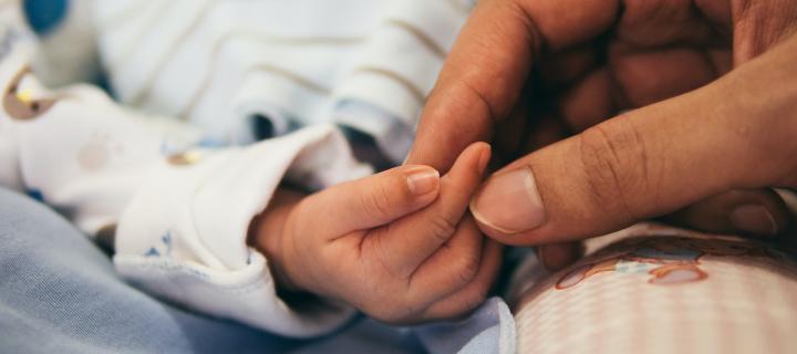 Newborn baby's hand being held by an adult