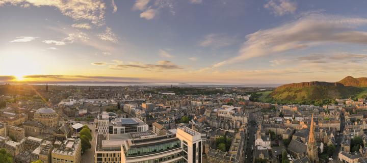Drone image of George Square buildings, the city, Arthur's Seat and the Firth of Forth in the background.