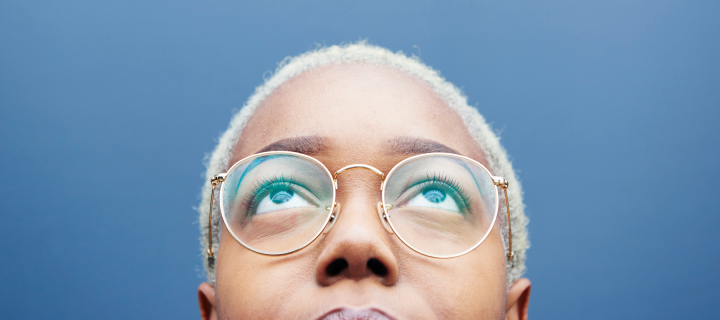 close up of a person head. They are looking up and wearing glasses.