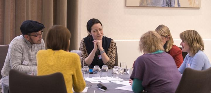 Group of adults - some researchers and some PPI members - sat around a table conversing