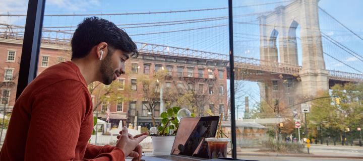 Man taking part in an online call with view of Brooklyn Bridge behind