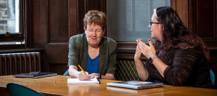 Rachel O'Neill and Alison Hendry at table using sign language