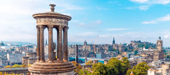 A view of Edinburgh city from Calton Hill on a sunny day, with the Dugald Stewart Monument in the foreground