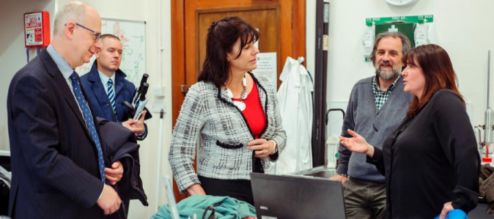 University of Edinburgh academics in a lab with UK energy minister Claire Perry, standing behind a table with laptop