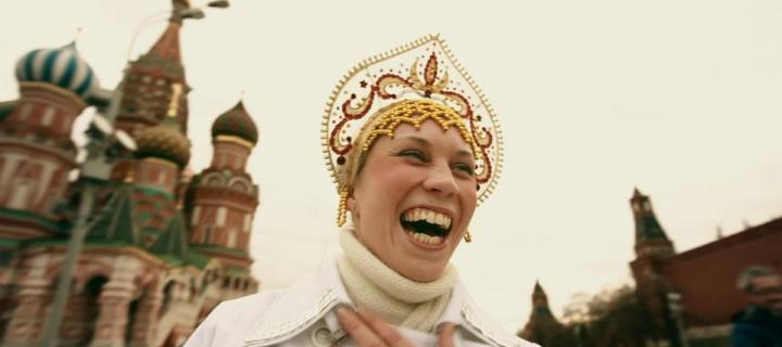 a woman in traditional Russian religious dress stands on Red Square laughing 