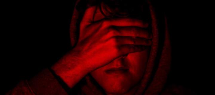 Red image of man with hand over face