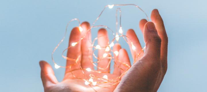 Two hands holding fairy lights