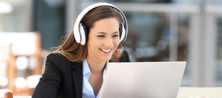 woman wearing headphone watches online lecture with laptop