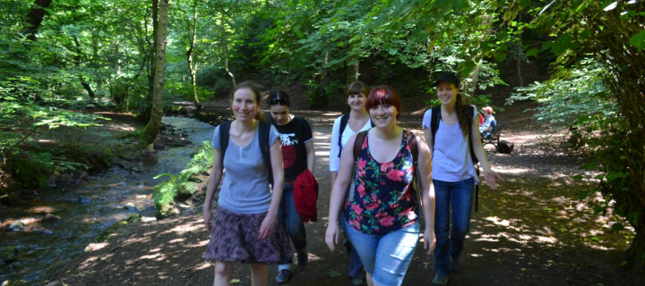 Julie and lab group members walking through a wood next to a river