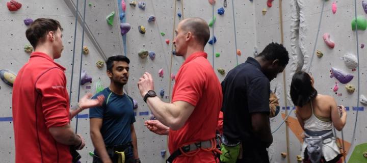 Group of people talking with climbing wall in the background