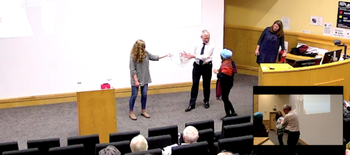 Professor Damien Mole uses two girls in a demonstration inside a lecture theatre.