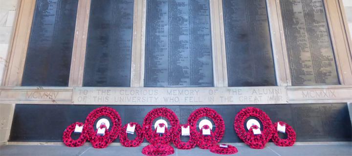 Memorial wall at Old College with multiple poppy wreaths laid in front of it.