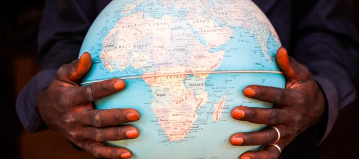 Hands holding a globe of the world depicting the African continent 