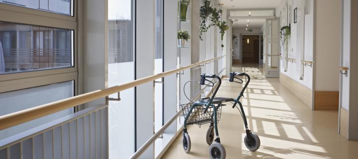 Walking frame in corridor of nursing home with windows on left hand side and a closed door at the end of the corridor