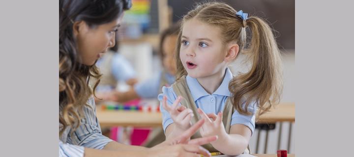 a child interacting with an adult in a classroom setting