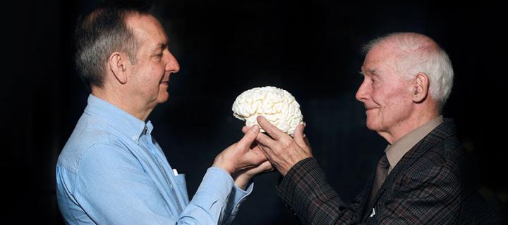 Photo of two men holding a model of a brain
