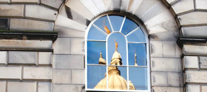 The 'golden boy' statue at Old College, reflected in the panes of a window