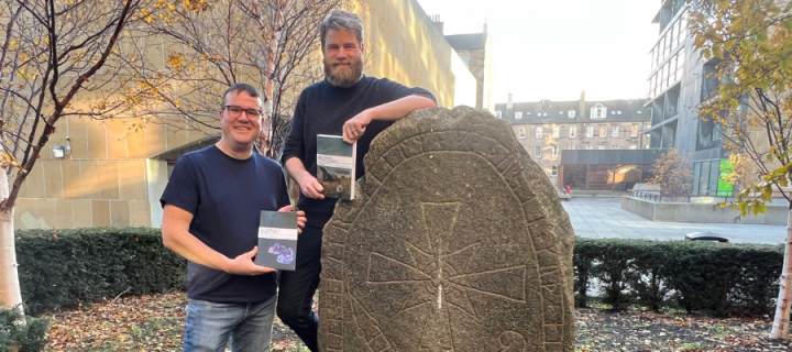 Ian Giles and Chris Cooijmans holding their books by the Swedish Runestone