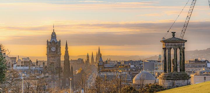 An autumn panorama of Edinburgh from top of Calton Hill, with Dugald Stewart Monument to the right and a distant crane