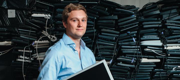 James Turing standing in front of a high stack of used PC hardware