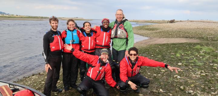 Students and teachers next to a river and kayak