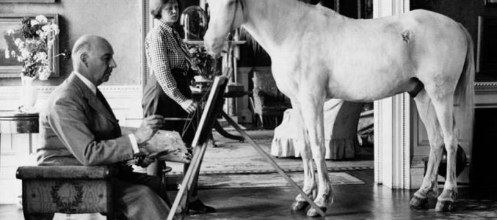 A man paints a picture of a white horse which stands in an elaborate room