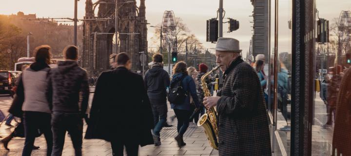 Princes Street in Edinburgh with a man playing saxophone