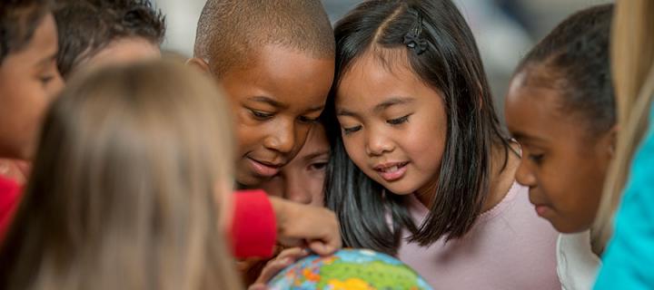 Photo of group of children looking a globe of the world