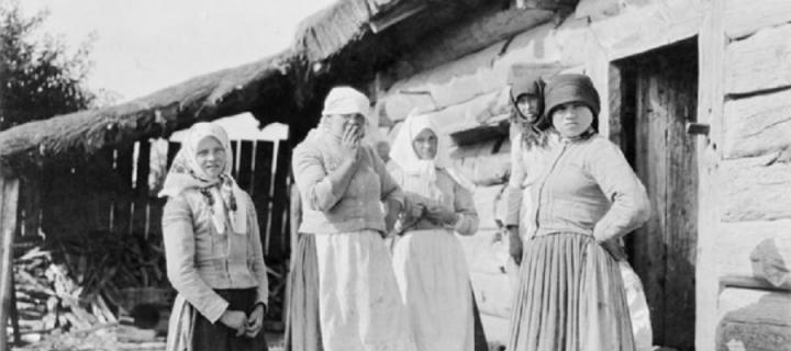 Five peasant women standing outside of log house