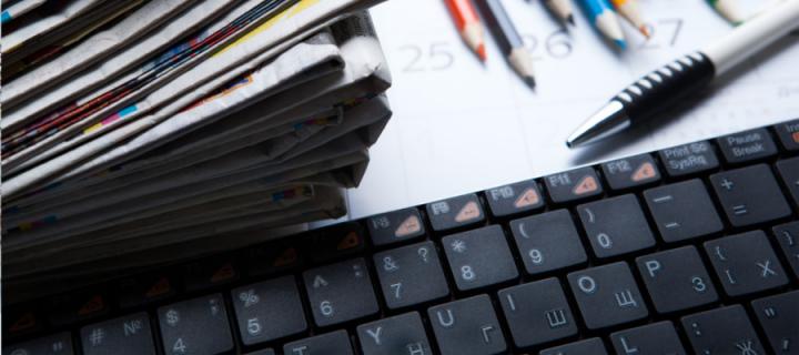 A stack of newspapers beside a Russian keyboard