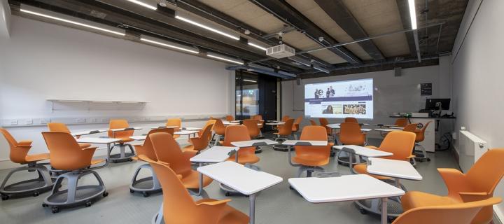 Image showing a teaching space with multiple orange chairs and clear desks.