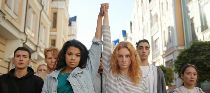 Two people stood with their hands clasped and arms raised in front of a larger group of people. 