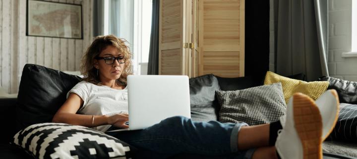 Woman sitting on sofa looking at laptop