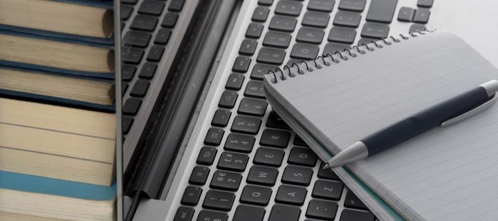 Open laptop with notepad and books. 