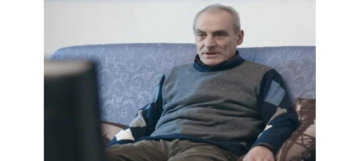 older man sits on couch