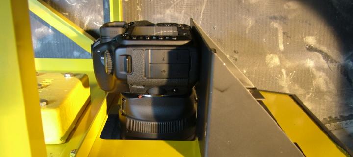 A Canon EOS camera in a yellow pod installation for an aircraft 