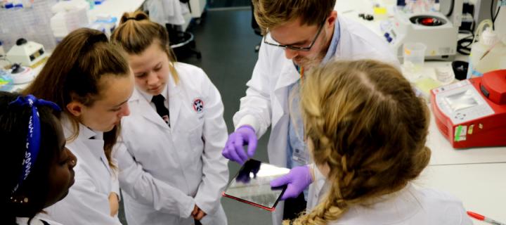 A PhD student explains a laboratory  technique to school pupils
