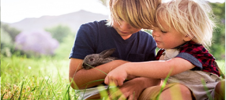 Photograph of two children cuddling a rabbit