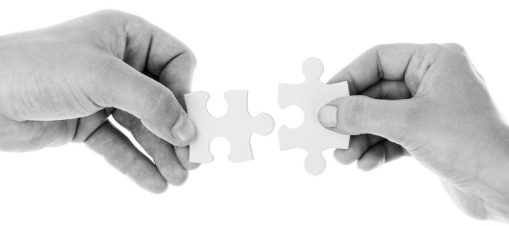 A picture of two hands holding a jigsaw puzzle pieces that fit together