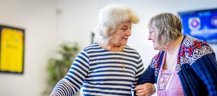 Two older women in conversation, linking arms