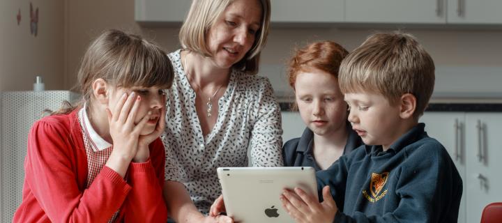Researcher looking at an ipad with 3 children
