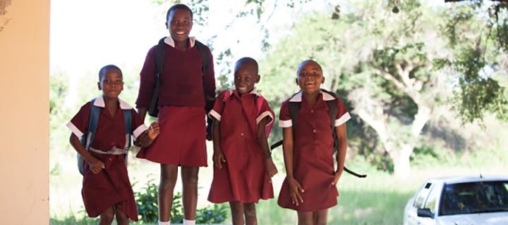 Four school children in uniform, jumping in the air