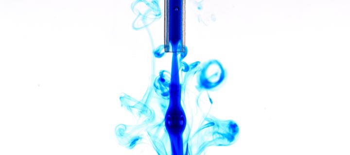 Blue dye liquid disperses against a white background