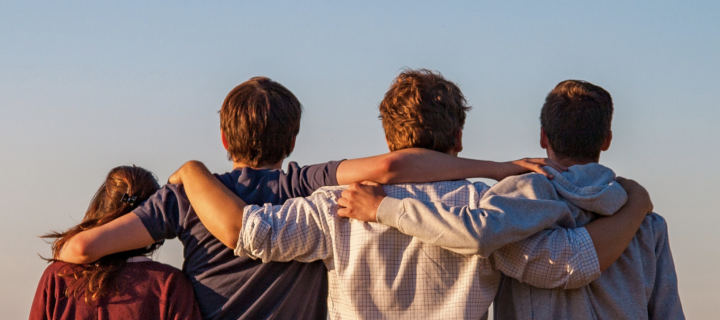 A group of people with their backs to camera, with their arms around each other