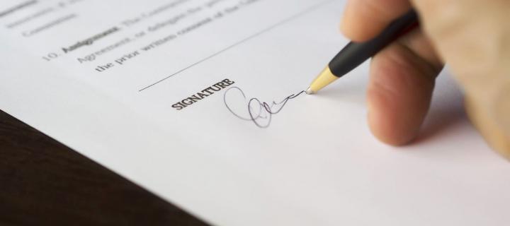 close-up of hand signing document with signature
