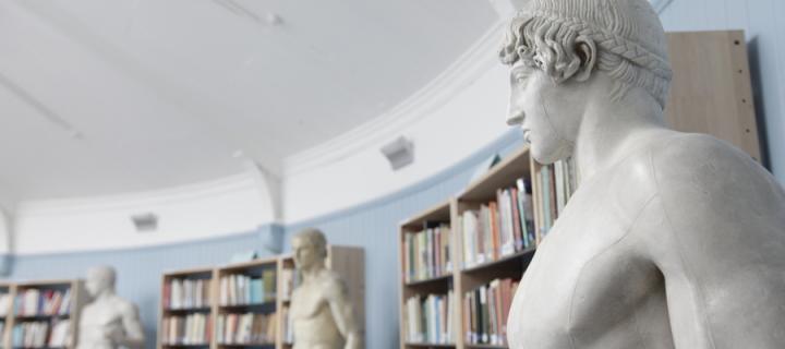 Classical statues in front of book cases