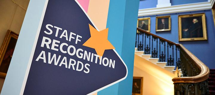 Staff awards banner in foreground with staircase in the Playfair Library in background
